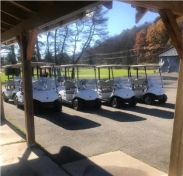 Fleet of white golf carts with fall foliage at Genegantslet Golf Club