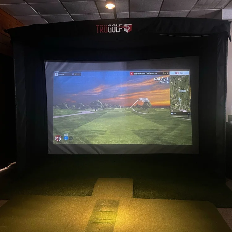 TruGolf simulator showing Torrey Pines with hitting mat in pine-paneled room