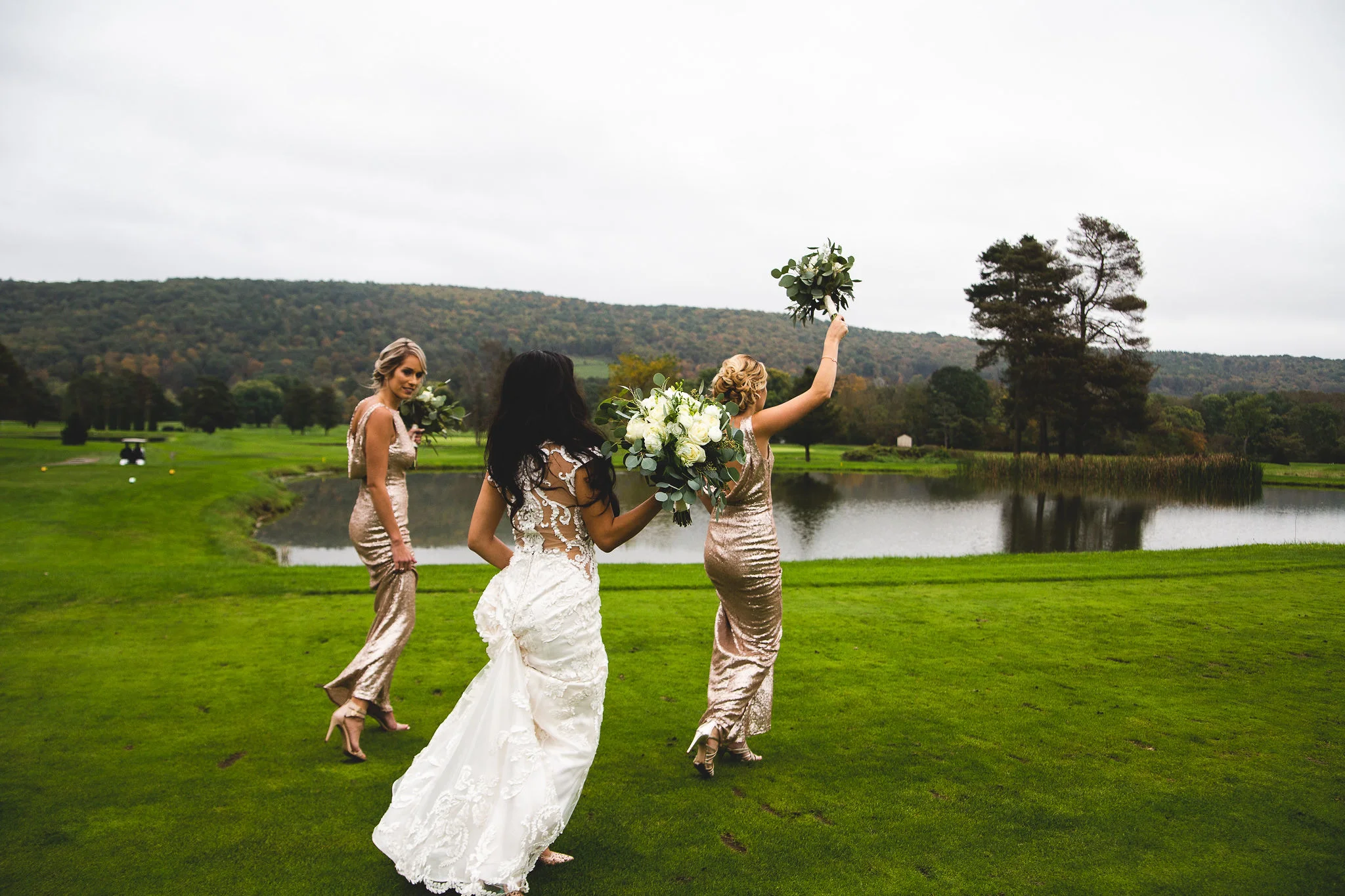 Bride and bridesmaids walking by the pond with fall mountains in background