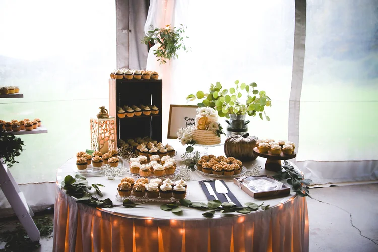Elegant dessert table with cupcakes, greenery, and warm lighting at a Genegantslet wedding