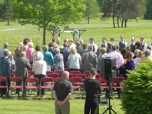 Outdoor ceremony in progress with green fairway behind